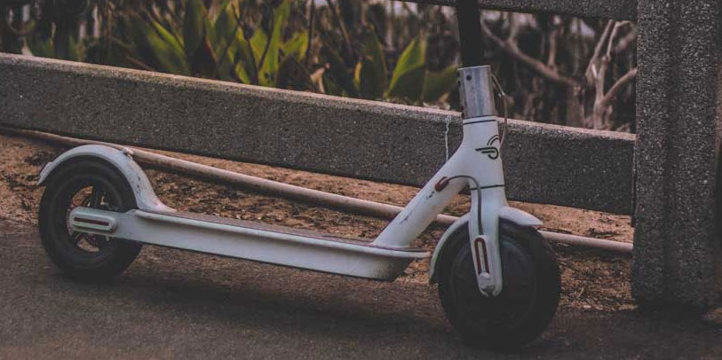 Weißer E-Scooter lehnt an Bordstein
