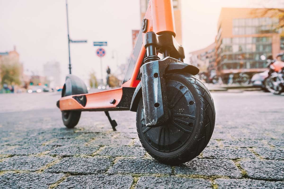 Das Vorderrad eines roten E-Scooters auf einer gefplasterten Straße