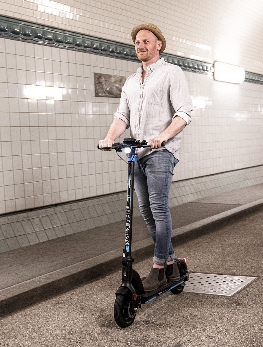 Mann mit Hut fährt URBAN E-Scooter in U-Bahn Tunnel